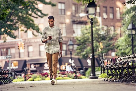 simsearch:6118-08243810,k - A man walking through a town square looking at his smart phone Stock Photo - Premium Royalty-Free, Code: 6118-08243805
