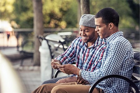 simsearch:6118-08243810,k - Two men sitting in a park, looking at a smart phone Stock Photo - Premium Royalty-Free, Code: 6118-08243811