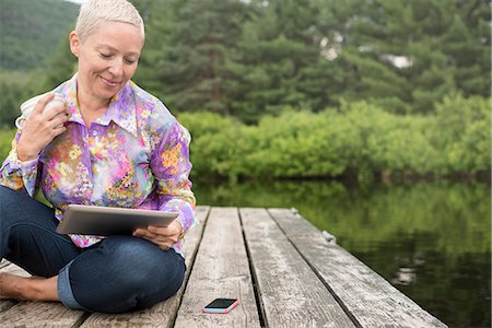 simsearch:6118-07122740,k - A woman sitting outdoors on a jetty using a digital tablet. Photographie de stock - Premium Libres de Droits, Code: 6118-08243926