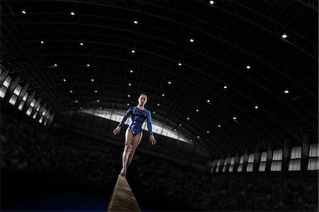 A young woman gymnast performing on the beam, balancing on a narrow piece of apparatus. Stock Photo - Premium Royalty-Free, Code: 6118-08352014