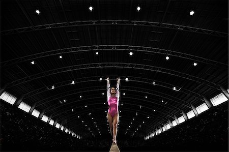 A young woman gymnast performing on the beam, balancing on a narrow piece of apparatus. Stock Photo - Premium Royalty-Free, Code: 6118-08352015
