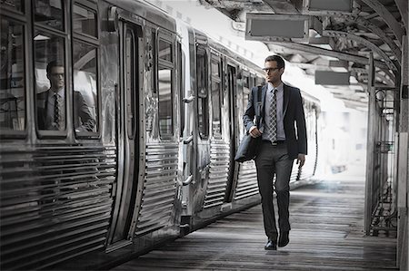 A working day. Businessman in a work suit and tie walking on the platform by a train carriage. Stock Photo - Premium Royalty-Free, Code: 6118-08399595