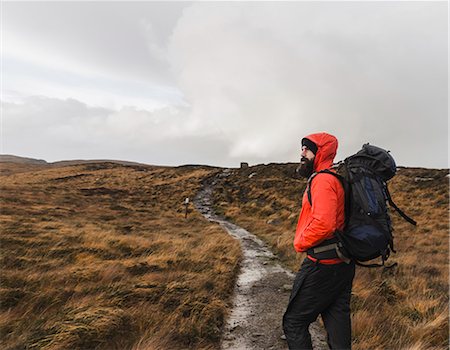 rugged landscape - A man in winter clothing, waterproof jacket and rucksack in open countryside by a path. Stock Photo - Premium Royalty-Free, Code: 6118-08399670