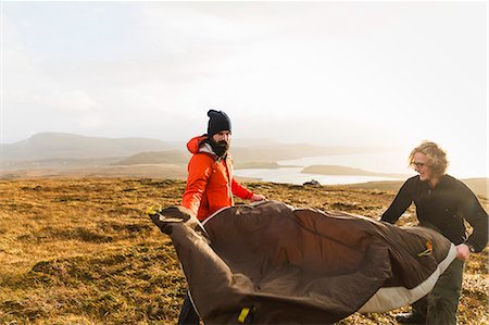 simsearch:6118-08399715,k - Two men holding and putting up a small tent in open space. Wild camping. Stock Photo - Premium Royalty-Free, Code: 6118-08399675