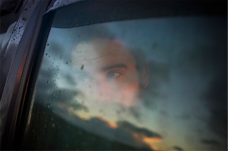 simsearch:6118-08399701,k - A man sitting in a car looking out. Reflections of the sunset sky on the window. Stock Photo - Premium Royalty-Free, Code: 6118-08399705