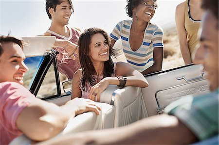A group of friends in a pale blue convertible on the open road, driving across a dry flat plain surrounded by mountains. Photographie de stock - Premium Libres de Droits, Code: 6118-08488144
