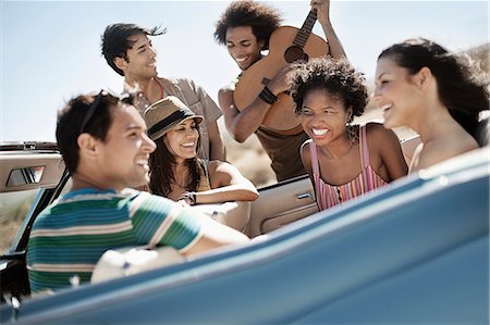 A group of friends in a pale blue convertible on the open road, driving across a dry flat plain surrounded by mountains. Photographie de stock - Premium Libres de Droits, Code: 6118-08488167