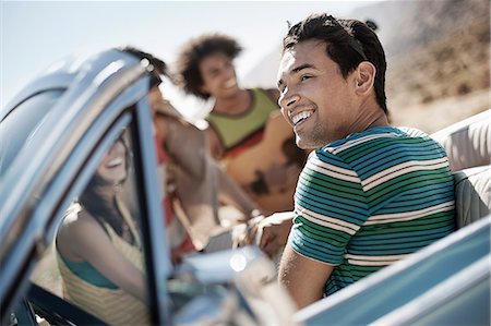 A group of friends in a pale blue convertible on the open road, driving across a dry flat plain surrounded by mountains. Photographie de stock - Premium Libres de Droits, Code: 6118-08488166