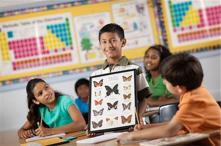 symbol for students education - A boy standing in front of classmates, holding up a frame with butterfly specimens. Stock Photo - Premium Royalty-Free, Code: 6118-08488290