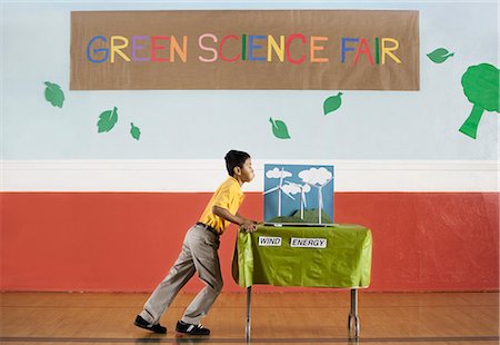 symbol for students education - A boy pushing a table into a room at the Green Science Fair. Stock Photo - Premium Royalty-Free, Code: 6118-08488232