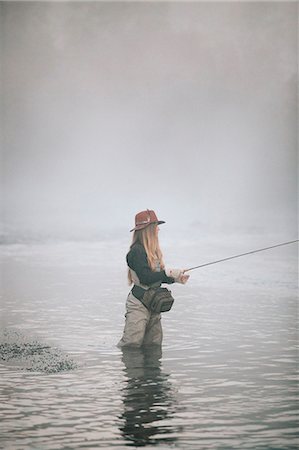 simsearch:6118-08521813,k - A woman fisherman fly fishing, standing in waders in thigh deep water. Stock Photo - Premium Royalty-Free, Code: 6118-08488418