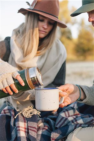 A woman pouring a hot drink from a vacuum flask into a cup on a winter picnic. Stock Photo - Premium Royalty-Free, Code: 6118-08488424