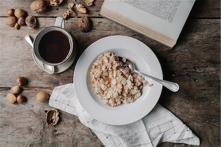 simsearch:6118-08521776,k - A table with a cup of coffee, bowl of muesli, nuts and an open book. Stock Photo - Premium Royalty-Free, Code: 6118-08521782