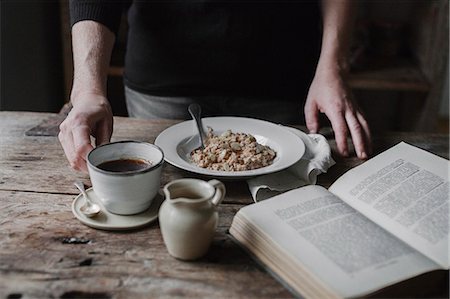 simsearch:6118-08521776,k - A person at a table with a cup of coffee, bowl of muesli and an open book. Stock Photo - Premium Royalty-Free, Code: 6118-08521784