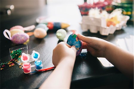 simsearch:6118-08521776,k - A child decorating eggs at Easter with glitter, glue and paint. Stock Photo - Premium Royalty-Free, Code: 6118-08660000