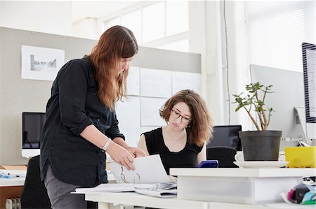 pult - A modern office. Two women, one standing and one seated, discussing paperwork. Stockbilder - Premium RF Lizenzfrei, Bildnummer: 6118-08797559