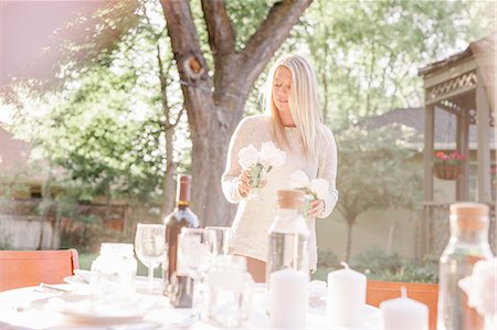 salt lake city - Blond woman setting a table in a garden, candles and vases with pink roses. Stock Photo - Premium Royalty-Free, Code: 6118-08725537