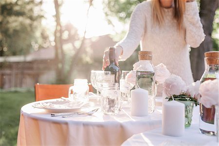 salt lake city - Woman setting a table in a garden, candles and a vase with pink roses. Stock Photo - Premium Royalty-Free, Code: 6118-08725535
