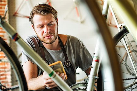 southern california - A man working in a bicycle repair shop, checking his smart phone. Photographie de stock - Premium Libres de Droits, Code: 6118-08725703