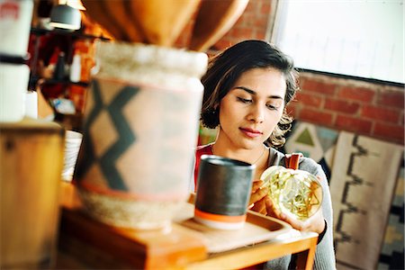 Young woman in a shop, looking at a drinking glass. Stock Photo - Premium Royalty-Free, Code: 6118-08725733