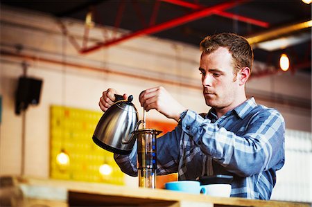 Specialist coffee shop. A man pouring hot water into a coffee percolator. Stock Photo - Premium Royalty-Free, Code: 6118-08725886