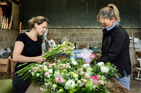 simsearch:6118-08202525,k - Commercial flower arranging. Two women at a workbench creating floral table decorations and arrangements. Stock Photo - Premium Royalty-Free, Code: 6118-08725974