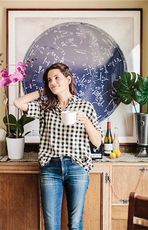 Woman with long brown hair, wearing a chequered shirt and jeans, holding a mug. Foto de stock - Sin royalties Premium, Código: 6118-08729154