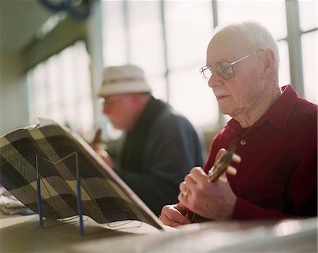 Two elderly men playing ukulele instruments in a senior center. Stock Photo - Premium Royalty-Free, Code: 6118-08860607