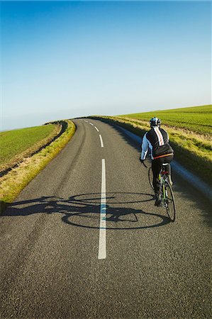 simsearch:695-03386286,k - A cyclist pedalling along a country road, rear view. Stock Photo - Premium Royalty-Free, Code: 6118-08882951