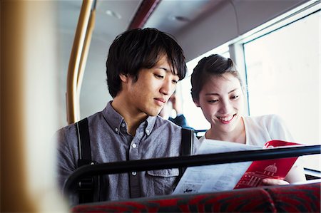 Young Japanese man and woman enjoying a day out in London, riding on a double decker bus. Stock Photo - Premium Royalty-Free, Code: 6118-08827429