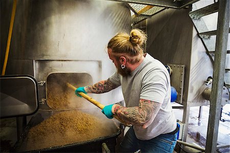 Man scraping spent grain from a large kettle in a brewery. Stock Photo - Premium Royalty-Free, Code: 6118-08971380