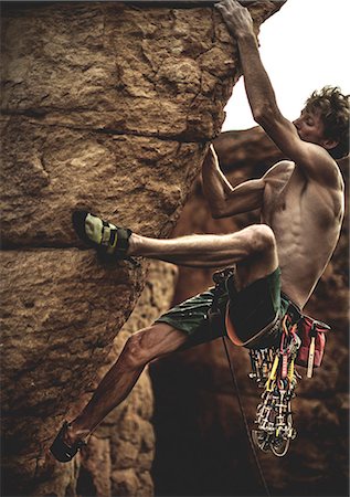 simsearch:6118-09039107,k - Mountaineer with a bare chest climbing a rock formation with carabiners and rope. Stock Photo - Premium Royalty-Free, Code: 6118-08991343
