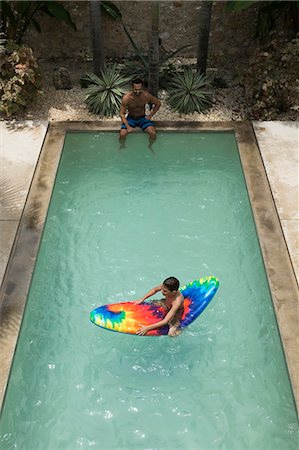 simsearch:693-06020764,k - High angle shot of a boy sitting on a pool raft, watched by a man at the edge of swimming pool. Photographie de stock - Premium Libres de Droits, Code: 6118-08991467