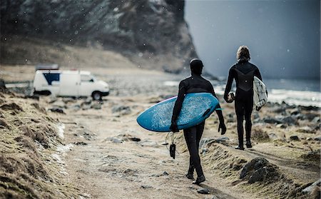 simsearch:6118-09039107,k - Two surfers wearing wetsuits and carrying surfboards walking towards a van. Stock Photo - Premium Royalty-Free, Code: 6118-08991415