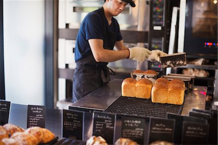 simsearch:649-06165027,k - Man working in a bakery, placing freshly baked loaves of bread on a tray. Stock Photo - Premium Royalty-Free, Code: 6118-09079240