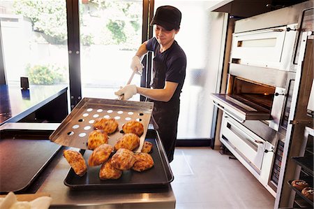 snack shop - Man working in a bakery, placing freshly baked rolls on baking tray. Stock Photo - Premium Royalty-Free, Code: 6118-09079267