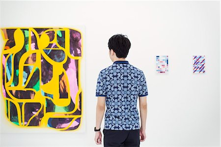 simsearch:693-05552760,k - Rear view of man with short black hair wearing blue shirt standing in art gallery, looking at abstract modern painting. Stock Photo - Premium Royalty-Free, Code: 6118-09079468