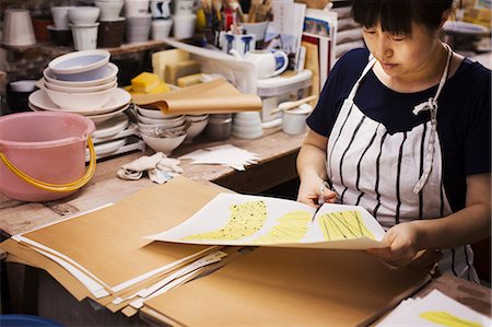 simsearch:859-06405000,k - Woman sitting in a Japanese porcelain workshop, cutting out design patterns with a pair of scissors. Stock Photo - Premium Royalty-Free, Code: 6118-09079414