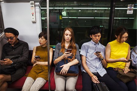 Five people sitting sidy by side on a subway train, Tokyo commuters. Stock Photo - Premium Royalty-Free, Code: 6118-09079662