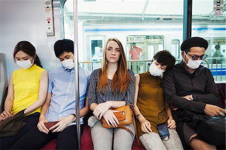 Five people wearing dust masks sitting sidy by side on a subway train, Tokyo commuters. Stock Photo - Premium Royalty-Free, Code: 6118-09079667