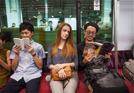 Three people sitting sidy by side on a subway train, reading,Tokyo commuters. Stock Photo - Premium Royalty-Free, Code: 6118-09079675