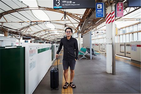 simsearch:841-07083701,k - Smiling man with wheeled suitcase standing on the platform of a subway station, Tokyo commuter. Stock Photo - Premium Royalty-Free, Code: 6118-09079683