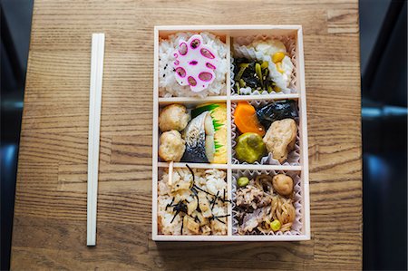 simsearch:6118-07808971,k - High angle close up of Bento box with traditional Japanese foods and chopsticks on a wooden table. Stock Photo - Premium Royalty-Free, Code: 6118-09079807
