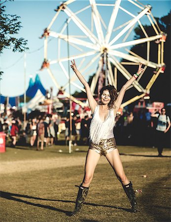 popular music concert - Young woman at a summer music festival wearing golden sequinned hot pants, face painted, smiling at camera, arms raised. Stock Photo - Premium Royalty-Free, Code: 6118-09018297