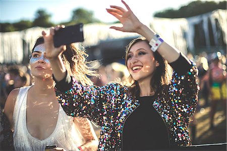 popular music concert - Young smiling woman at a summer music festival wearing multi-coloured sequinned jacket, taking picture with smartphone. Stock Photo - Premium Royalty-Free, Code: 6118-09018295