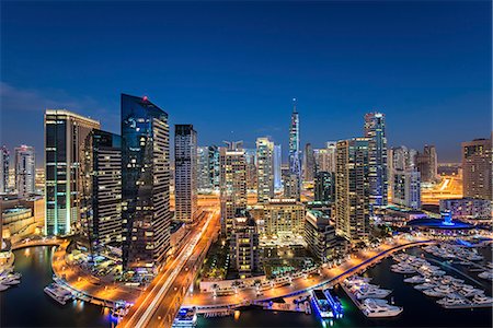 Cityscape of Dubai, United Arab Emirates at dusk, with illuminated skyscrapers and the marina in the foreground. Stock Photo - Premium Royalty-Free, Code: 6118-09028215