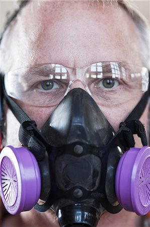 Close up view of Caucasian man factory worker wearing safety glasses and respirator. Stock Photo - Premium Royalty-Free, Code: 6118-09140140