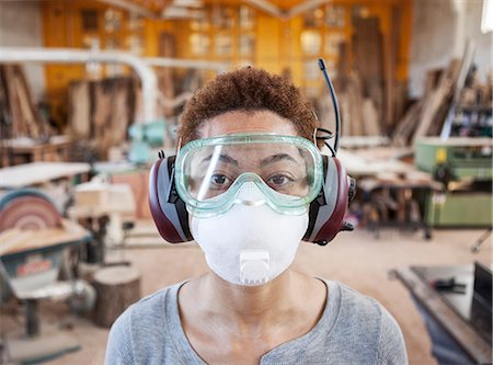 Close up view of black woman factory worker wearing safety glasses and dust nose mask in a woodworking factory. Stock Photo - Premium Royalty-Free, Code: 6118-09140142