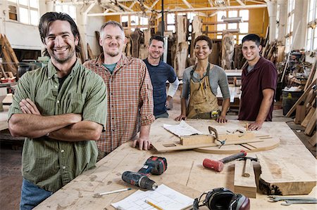 Team of multi-racial factory workers standing next to a work station in a large wood working factory. Stock Photo - Premium Royalty-Free, Code: 6118-09140155