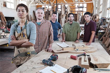 Team of multi-racial factory workers standing next to a work station in a large wood working factory. Stock Photo - Premium Royalty-Free, Code: 6118-09140156
